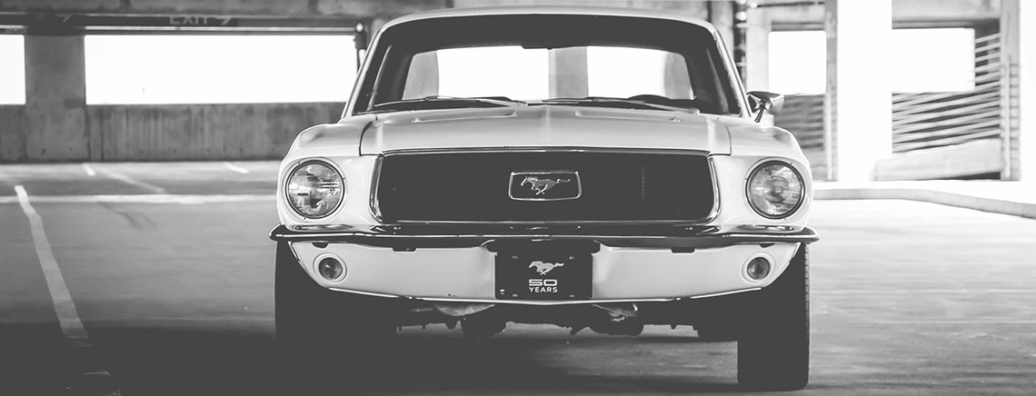 Front view of a classic Ford Mustang car parked in a garage.