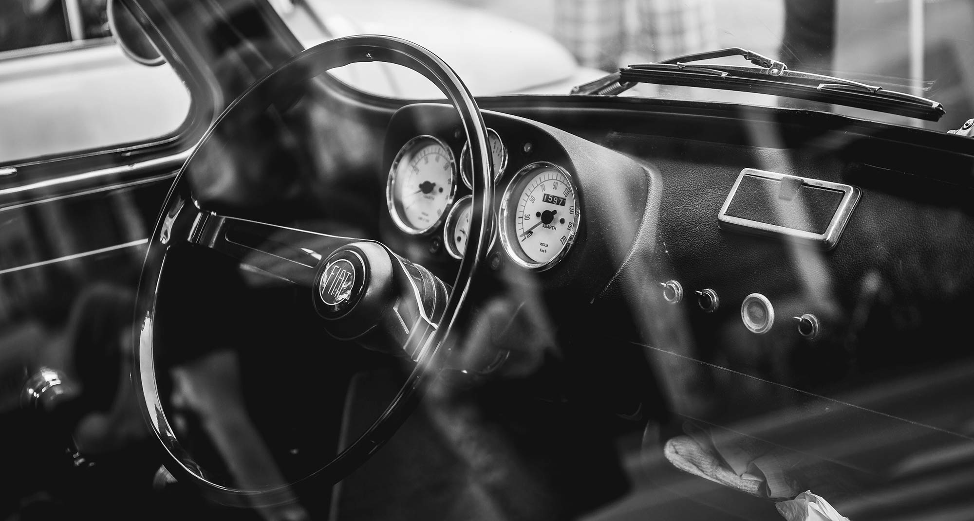 Vintage car interior with Fiat logo on the steering wheel with circular gauges on the dashboard.