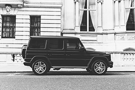 Black SUV parked on the side of a street in front of a building.