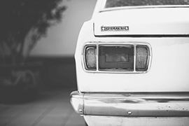 Rear end of a white vintage car in a black and white indoor setting.